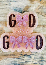 Load image into Gallery viewer, A handmade resin plaque spelling 'GOOD' with glittery pink bows, displayed on a rustic wooden surface.