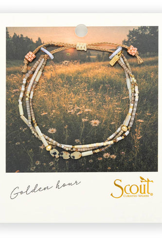 Necklace on a card with 'Scout' branding and 'Golden Hour' text, set against a nature-themed background.