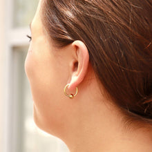 Load image into Gallery viewer, Close-up of a person wearing a gold hoop earring with a blurred background