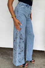 Load image into Gallery viewer, Person wearing blue lace-trimmed jeans against a white wall.
