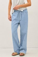 Load image into Gallery viewer, woman wearing light blue jeans with grey background