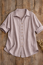Load image into Gallery viewer, Light brown button-up shirt on a wooden surface with dried flowers.