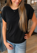 Load image into Gallery viewer, Woman wearing a black t-shirt and light blue jeans in a clothing store.