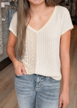 Load image into Gallery viewer, Woman wearing a beige knit top and blue jeans in a clothing store.