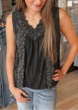 Load image into Gallery viewer, Woman wearing a black sleeveless top with floral details in a clothing store.
