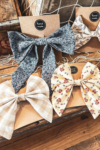 Set of decorative bows on a wooden surface with 'hand made' labels.
