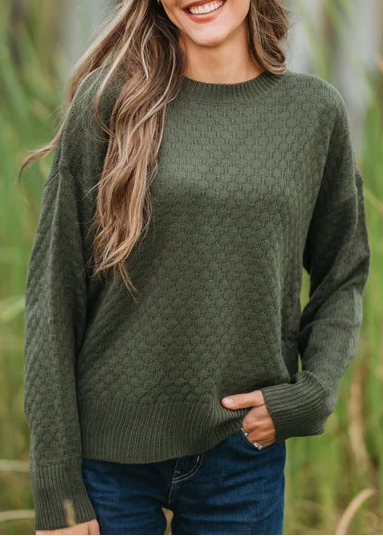 woman wearing olive green sweater in outdoor setting