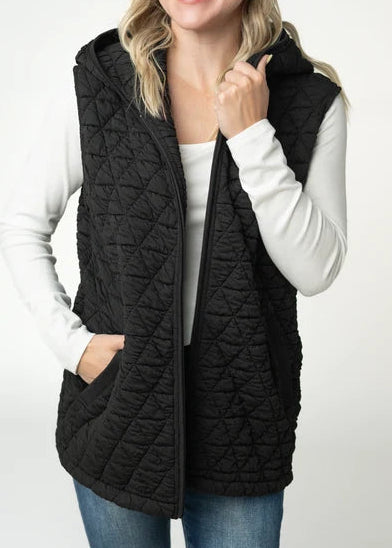 woman wearing black quilted vest in studio with grey background