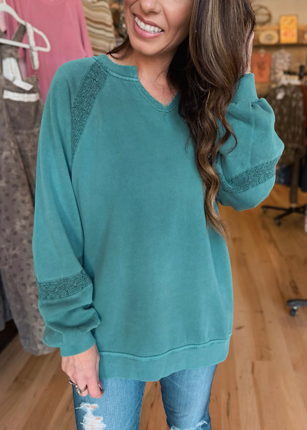 woman wearing teal sweatshirt in boutique setting