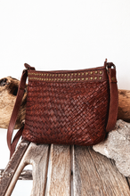 Load image into Gallery viewer, Brown woven handbag with studded details on a wooden surface