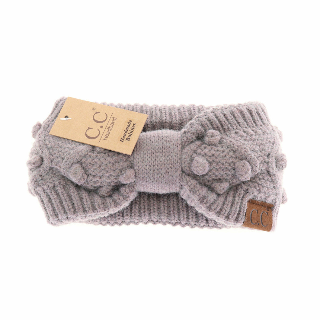 Gray knitted headband with pom-poms and C.C tag on a white background
