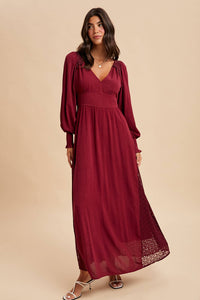 Woman wearing a burgundy dress with long sleeves on a beige background