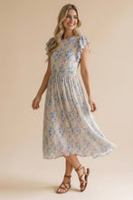 Load image into Gallery viewer, Woman wearing a floral dress against a beige background