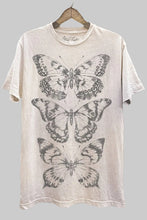 Load image into Gallery viewer, White t-shirt with butterfly designs on a wooden background