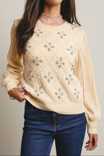 Load image into Gallery viewer, Woman wearing a beige sweater with floral patterns and blue jeans against a neutral background