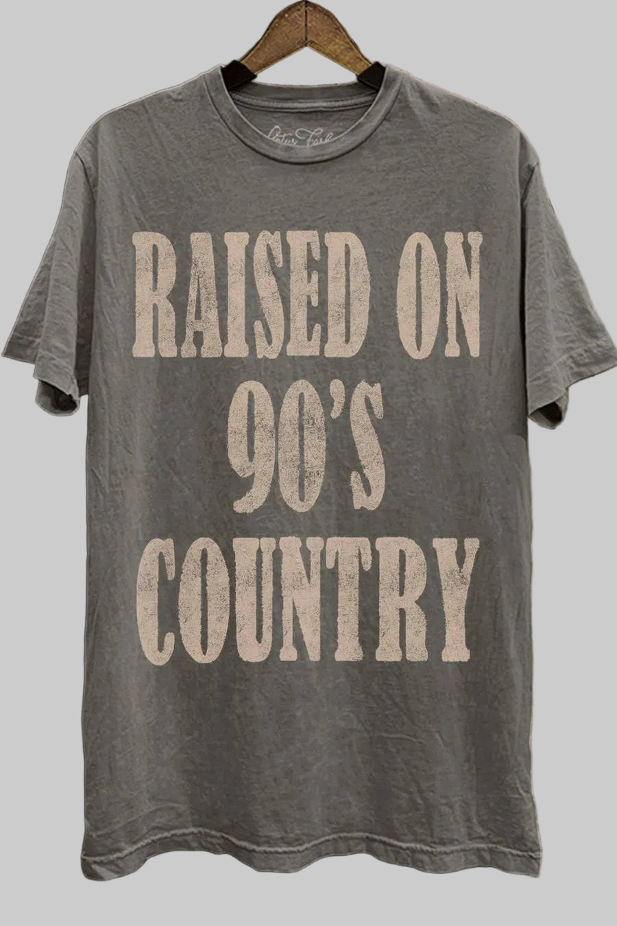 Gray t-shirt with 'Raised on 90's Country' text on a wooden background