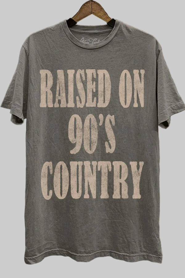 Gray t-shirt with 'Raised on 90's Country' text on a wooden background