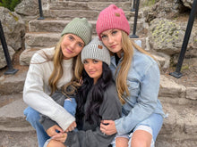 Load image into Gallery viewer, Three women sitting on stone steps wearing colorful beanies.