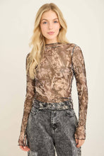 Load image into Gallery viewer, Woman wearing a camouflage long-sleeve top and gray jeans on a beige background