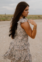 Load image into Gallery viewer, Woman in a floral dress standing on a gravel road with a field in the background