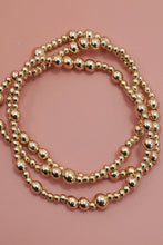 Load image into Gallery viewer, Two gold beaded bracelets on a pink background