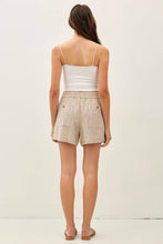 Load image into Gallery viewer, Woman wearing a white top and beige shorts on a plain background