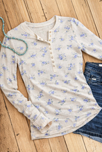 Load image into Gallery viewer, Floral long-sleeve shirt on a wooden surface with jeans and a necklace.