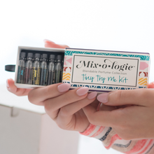 Load image into Gallery viewer, Hand holding a &#39;Mixologie&#39; perfume collection kit with small bottles inside.