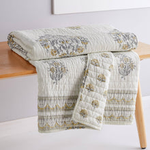 Load image into Gallery viewer, Floral patterned quilt draped over a wooden bench on a white background