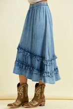 Load image into Gallery viewer, Blue denim skirt with ruffles worn by a person, paired with brown embroidered boots on a beige background.