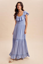 Load image into Gallery viewer, Woman wearing a blue dress with ruffled details on a beige background