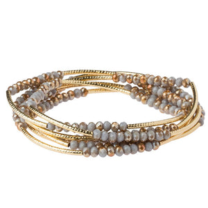Multi-layered bracelet with gold and gray beads on a white background