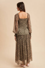 Load image into Gallery viewer, Woman wearing a long, patterned dress against a beige background
