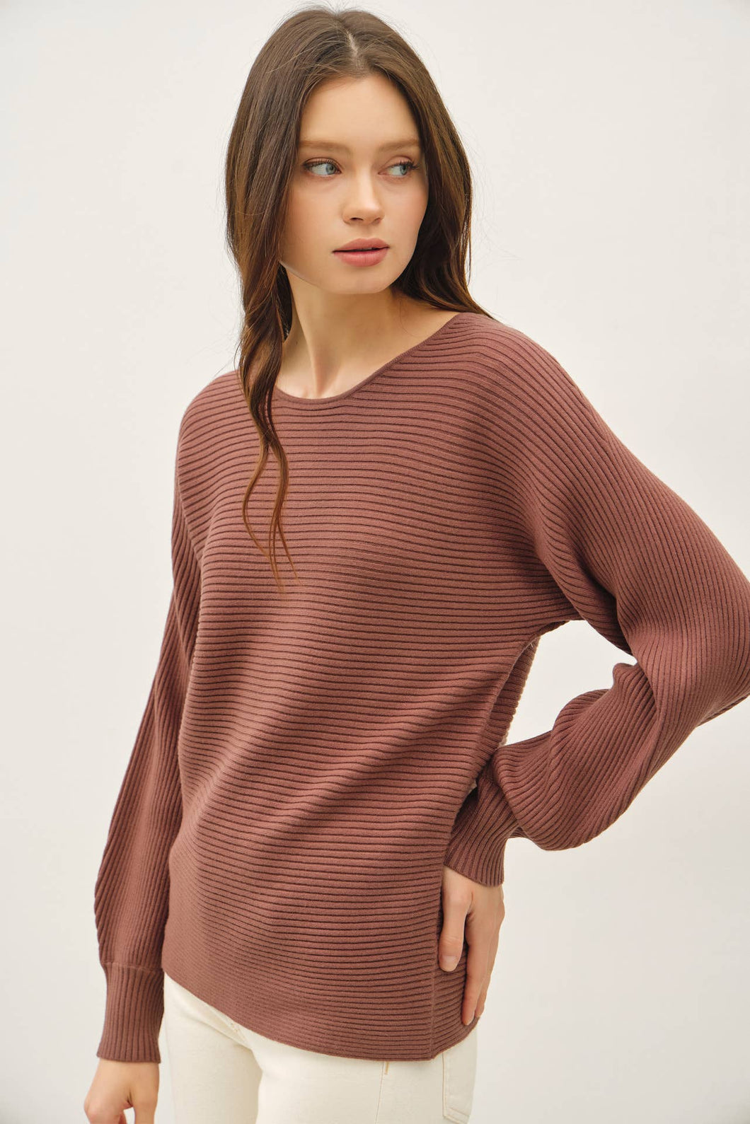 Woman wearing a brown sweater against a plain background