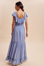 Load image into Gallery viewer, Woman wearing a blue dress with ruffled shoulders on a beige background