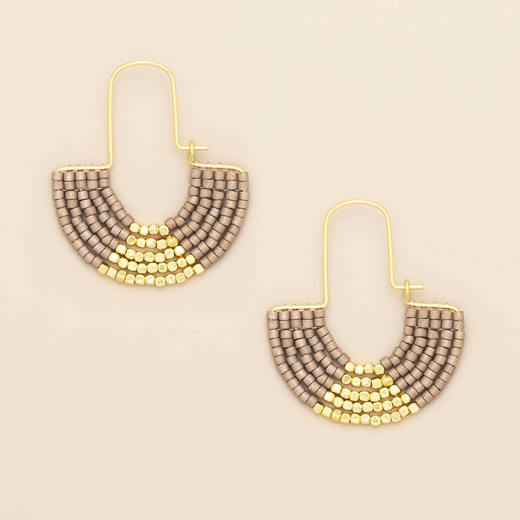 Pair of beaded earrings with gold and gray design on a beige background