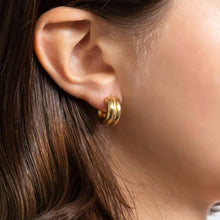 Load image into Gallery viewer, Close-up of an ear wearing a gold hoop earring with hair partially obscuring the view.