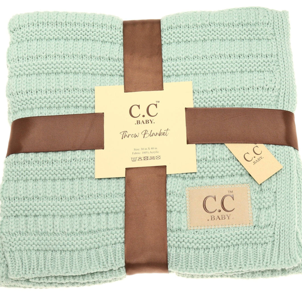 Folded green blanket with brown ribbon and C.C Baby label on a white background