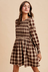 Woman wearing a plaid dress against a beige background