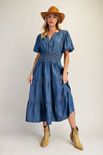 Load image into Gallery viewer, Woman wearing a blue dress with puff sleeves, a brown hat, and gold boots on a white background