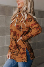 Load image into Gallery viewer, Woman wearing a brown floral hoodie against a gray tiled wall.