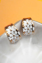 Load image into Gallery viewer, Pair of gold and white floral patterned earrings on a white surface with a yellow background