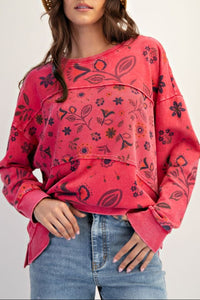 Woman wearing a red patterned sweater and straw hat on a plain background