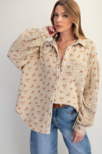 Woman wearing a floral blouse and jeans on a plain background