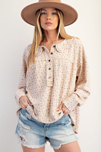 Woman wearing a patterned blouse, denim shorts, and a wide-brimmed hat against a white background