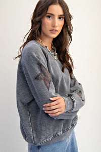 woman wearing grey sweatshirt with star patches on the sleeves