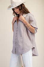 Load image into Gallery viewer, Woman wearing a light gray button-up shirt and white pants with a beige background