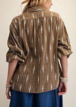 Load image into Gallery viewer, Person wearing a brown patterned shirt and blue skirt with a beige hat on a neutral background