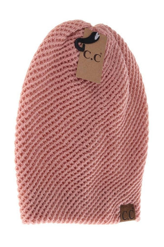 Pink knitted beanie with a brown tag on a white background
