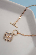 Load image into Gallery viewer, Gold necklace with a heart-shaped pendant on a white dish with a blue background